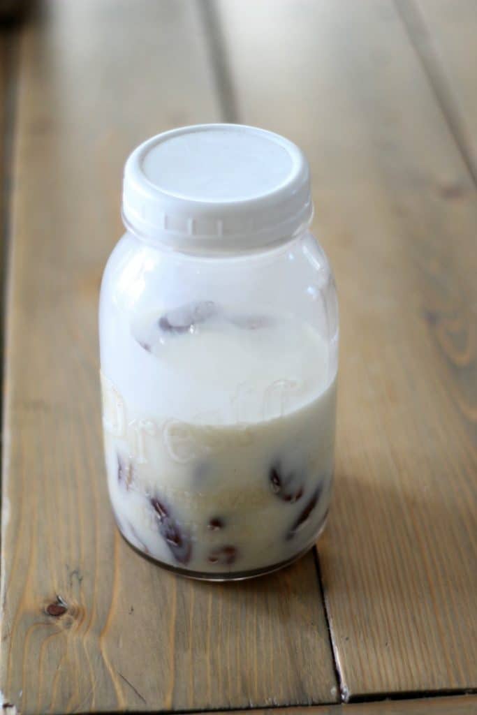 dates soaking in coconut milk in a mason jar with a white plastic lid