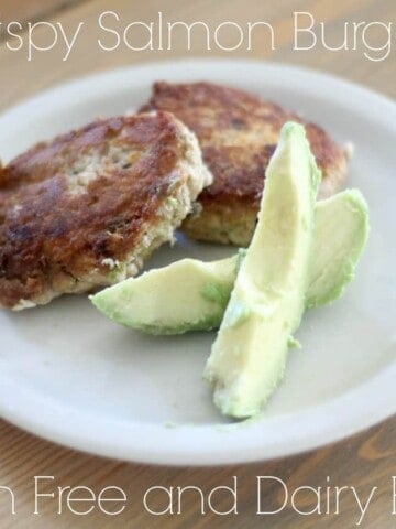 salmon burger on a white place with sliced avocado