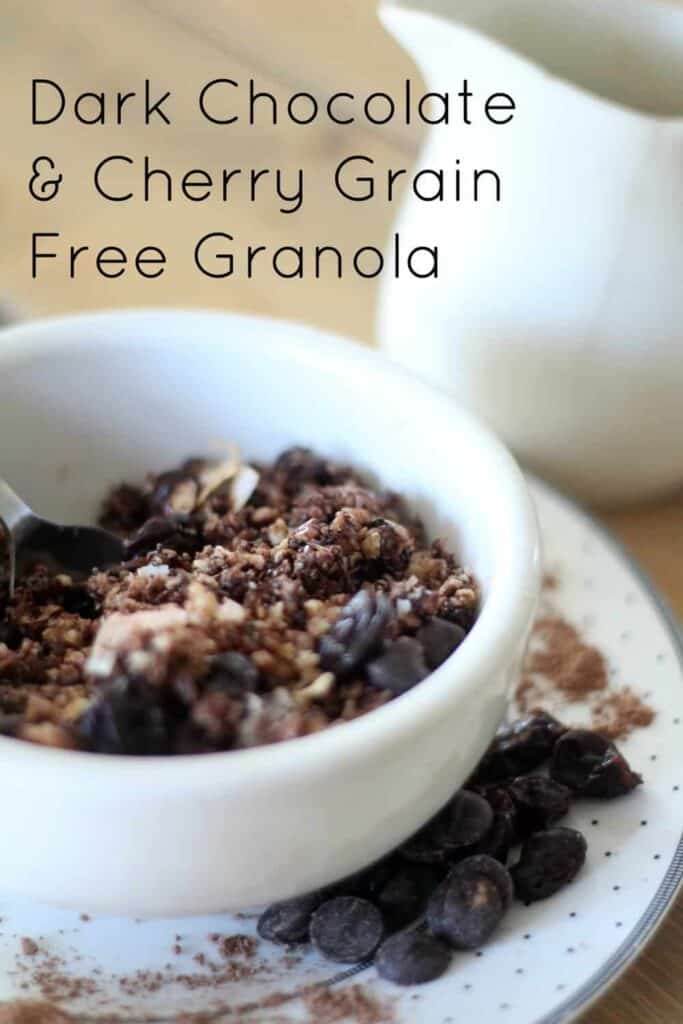 a white bowl filled with grain-free granola with chocolate chips and cherries on a silver and white polka dot plate