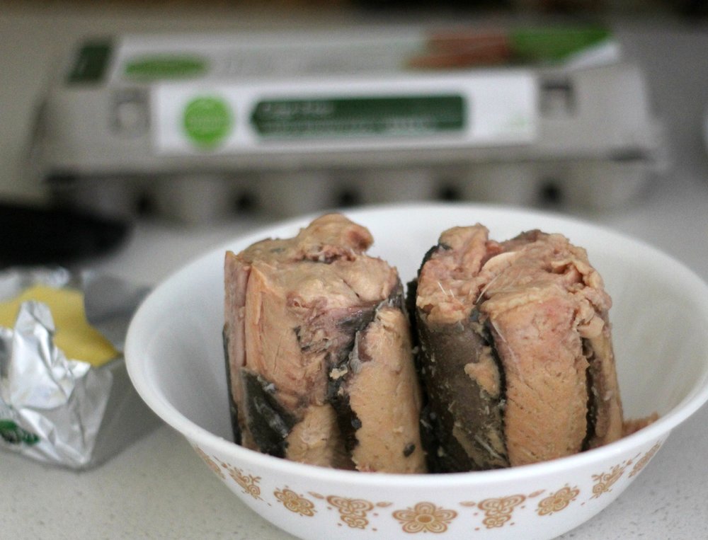 canned salmon in a bowl with butter to the left and a carton of eggs behind - making salmon burgers