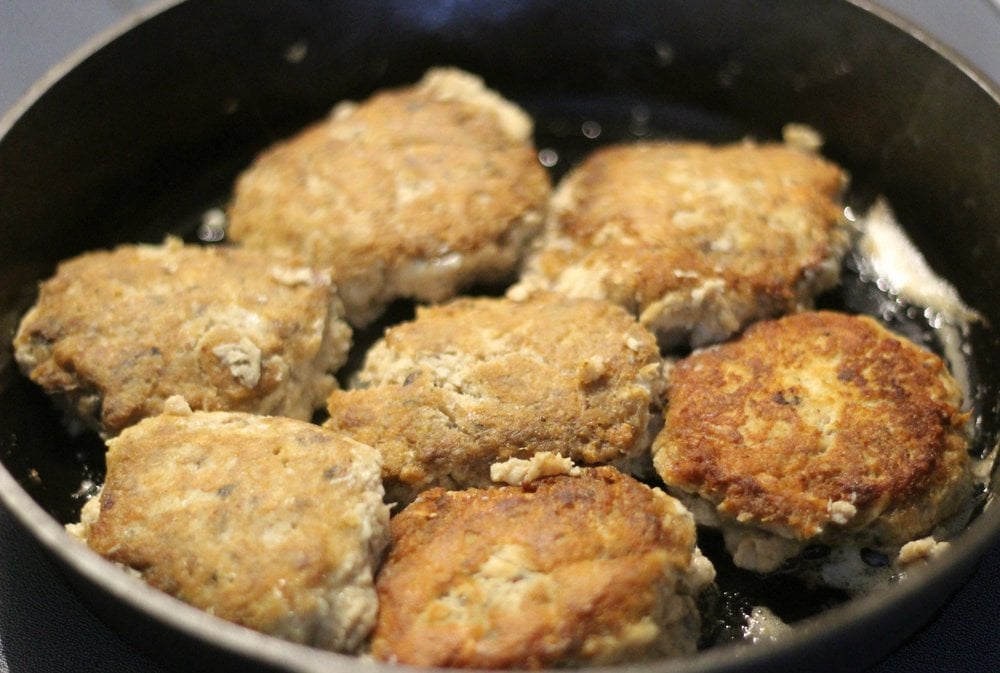 salmon burger frying in a cast iron skillet