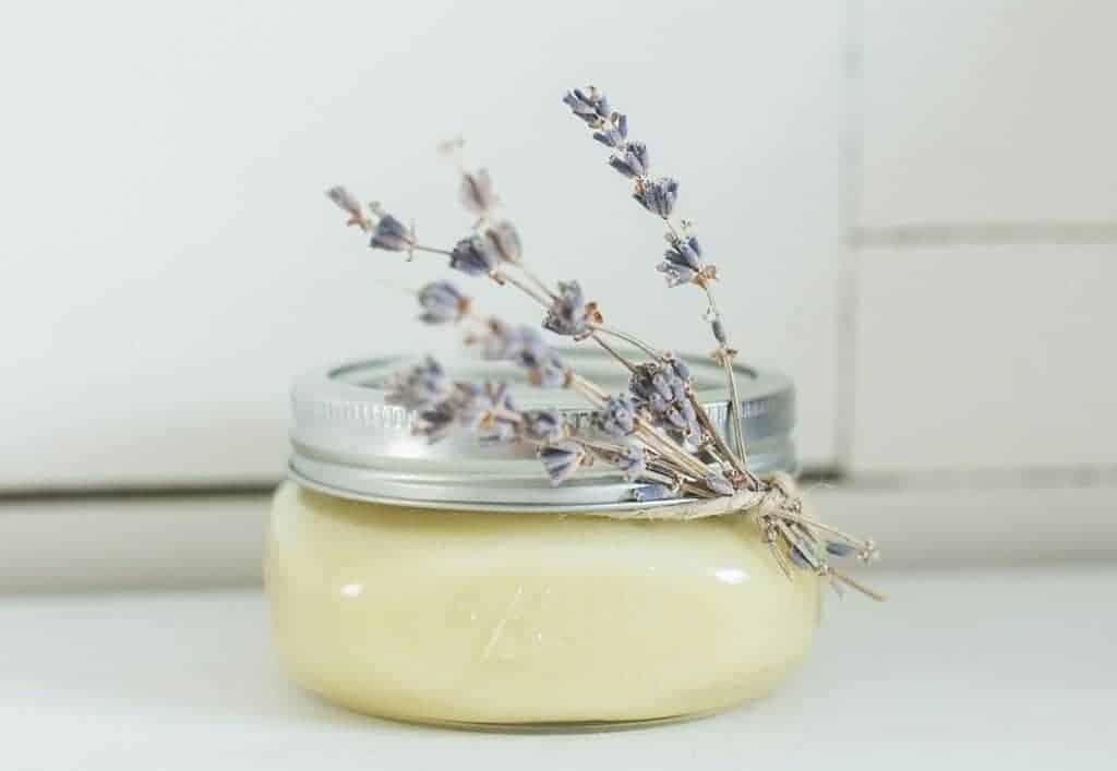 homemade sunscreen in a glass mason jar with lavender tied around the lid with twine