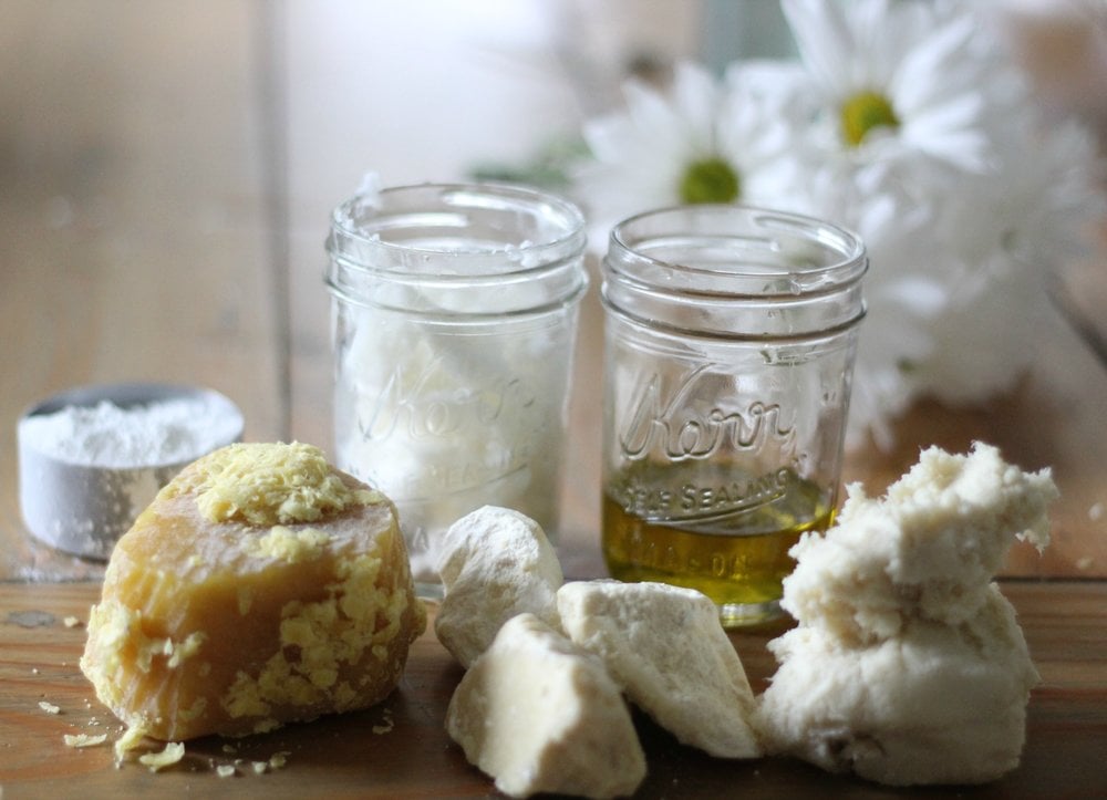 two jars of coconut oil and olive oil with shea butter, cocoa butter, beeswax and zinc oxide to make homemade sunscreen