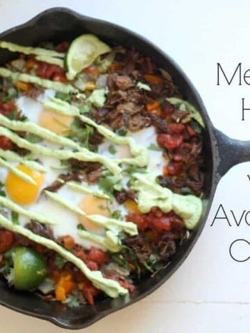 cast iron skillet with Mexican hash browns topped with eggs and avocado cream