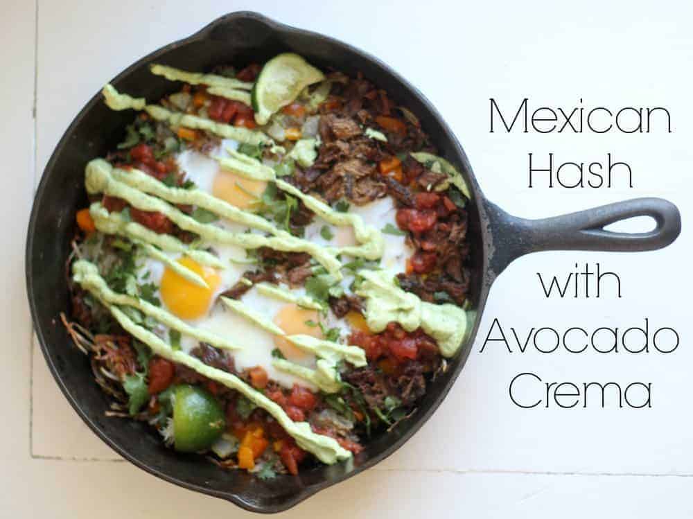 cast iron skillet with Mexican hash browns topped with eggs and avocado cream