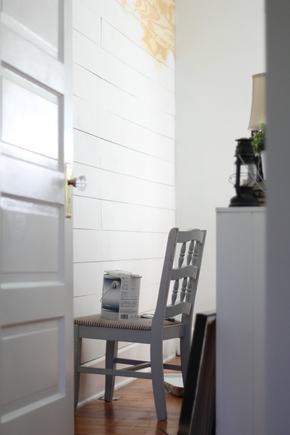 paint on a chair that is being painted onto a DIY Shiplap wall.