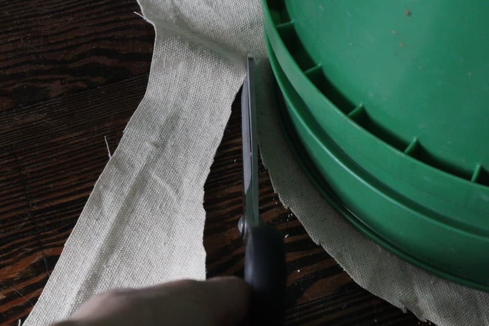 cutting out the fabric while using the bucket for the shape