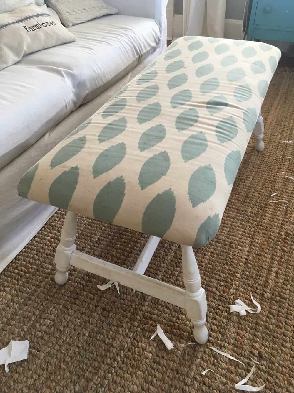 a white bench with a creamy and teal cushion top