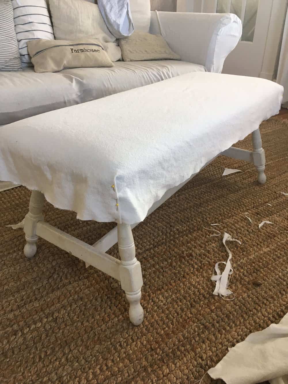 white drop cloth pined on top a white wood bench