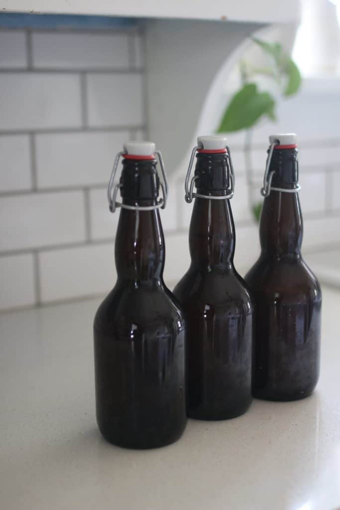 three bottles amber flip top bottles on a white countertop 