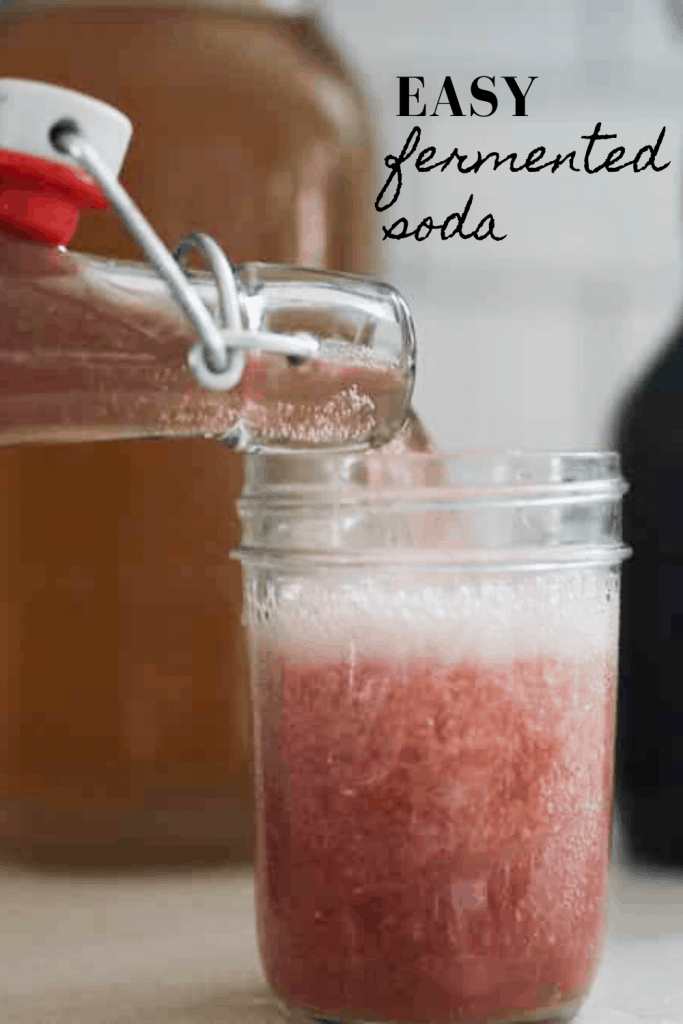 water kefir soda being poured into a mason jar on a white countertop