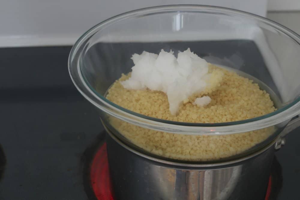 beeswax and coconut oil in a glass bowl over a pot of water