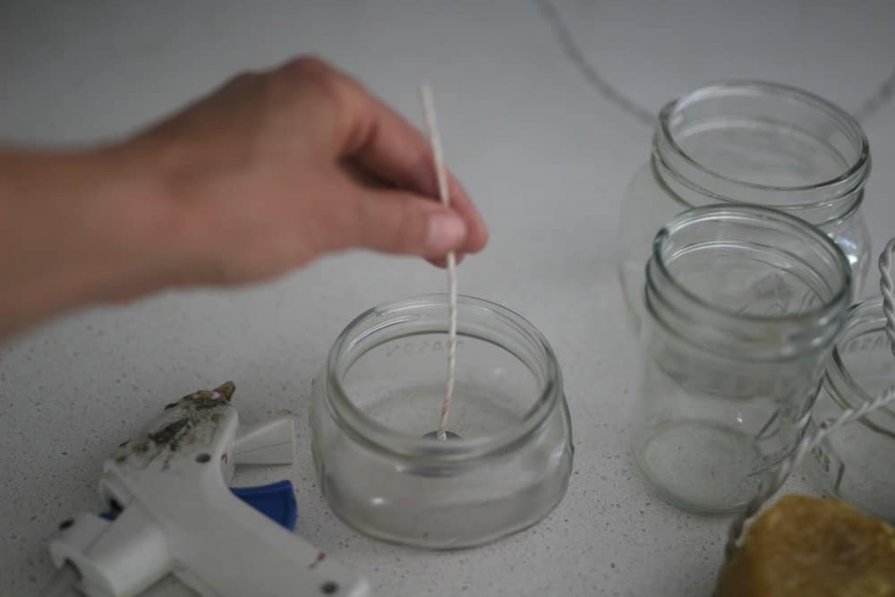 hot gluing wicks to the bottle of glass mason jars to make homemade candles