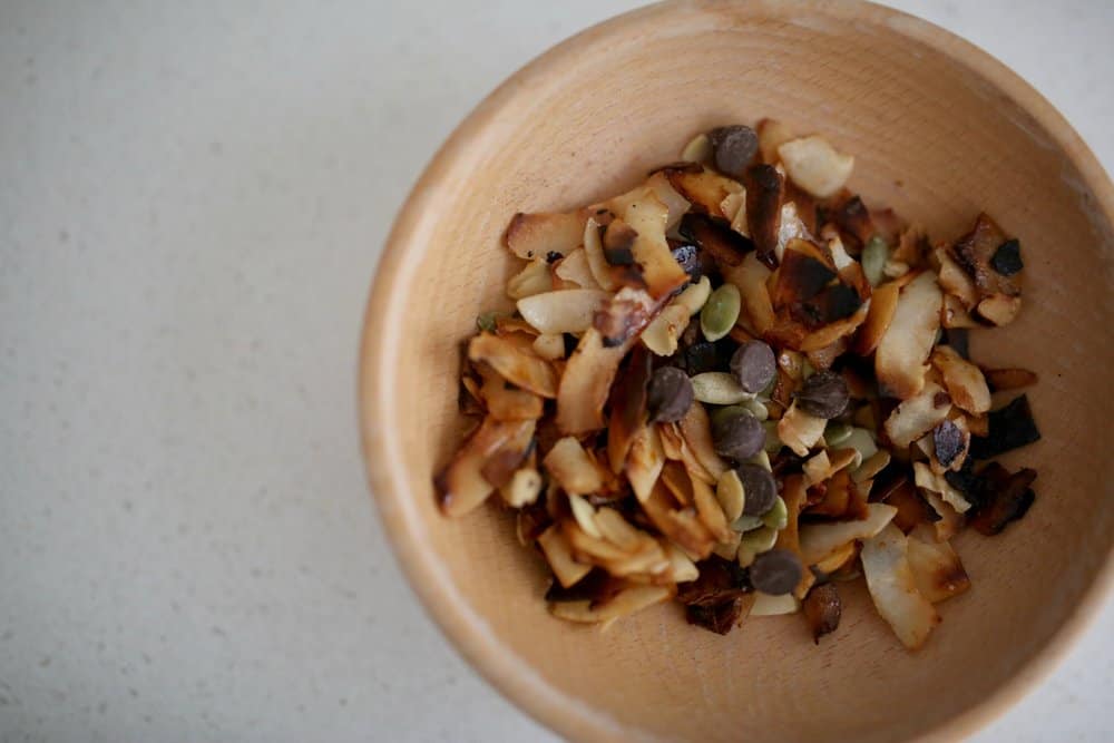 toasted coconut chips with pipits and chocolate chips in a tan bowl.