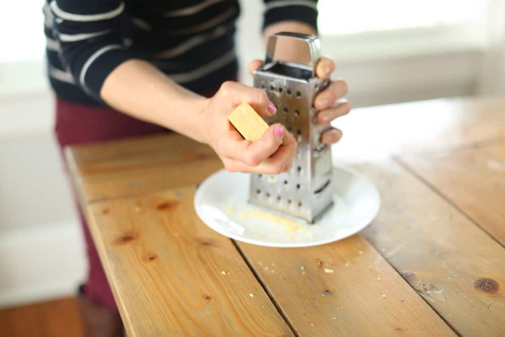 women creating Fels naphtha soap with a cheese grater on a plate to make homemade laundry soap