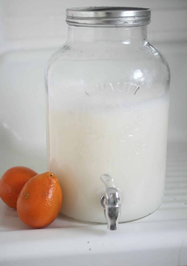 homemade laundry soap in a large glass drink dispenser with oranges to the left