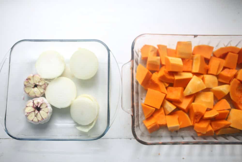 onions, garlic, and chopped butternut squash in glass baking dishes 