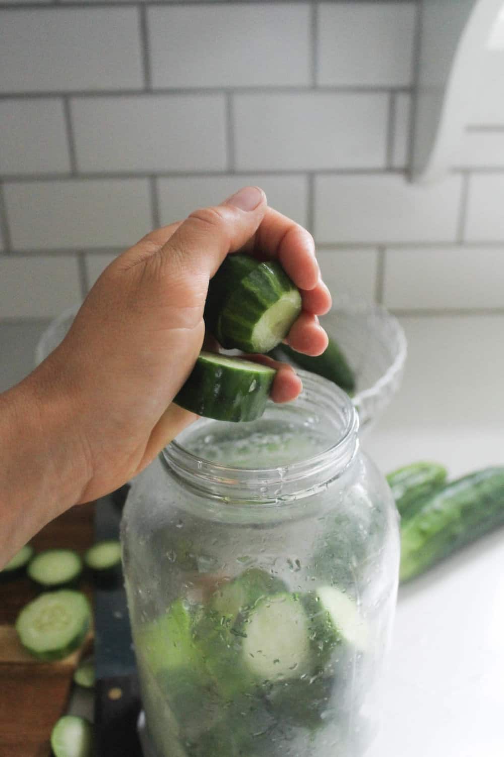 adding pickles to a mason jar to make easy fermented pickles