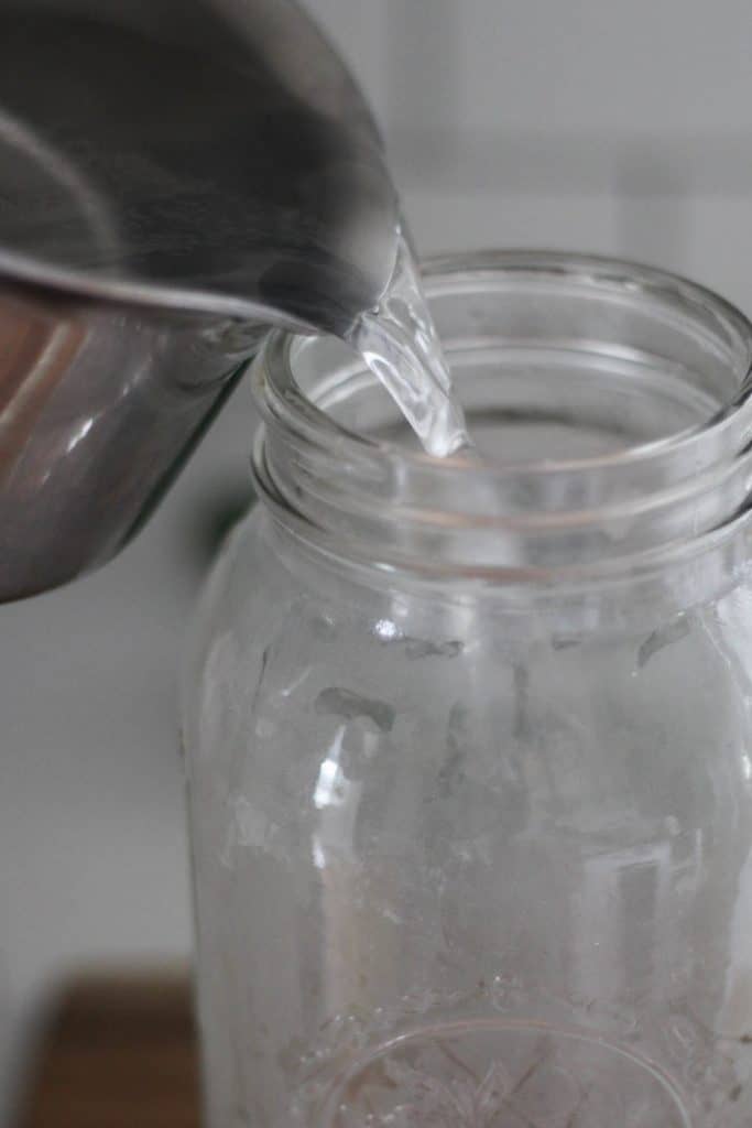 Pouring water into a glass jar.