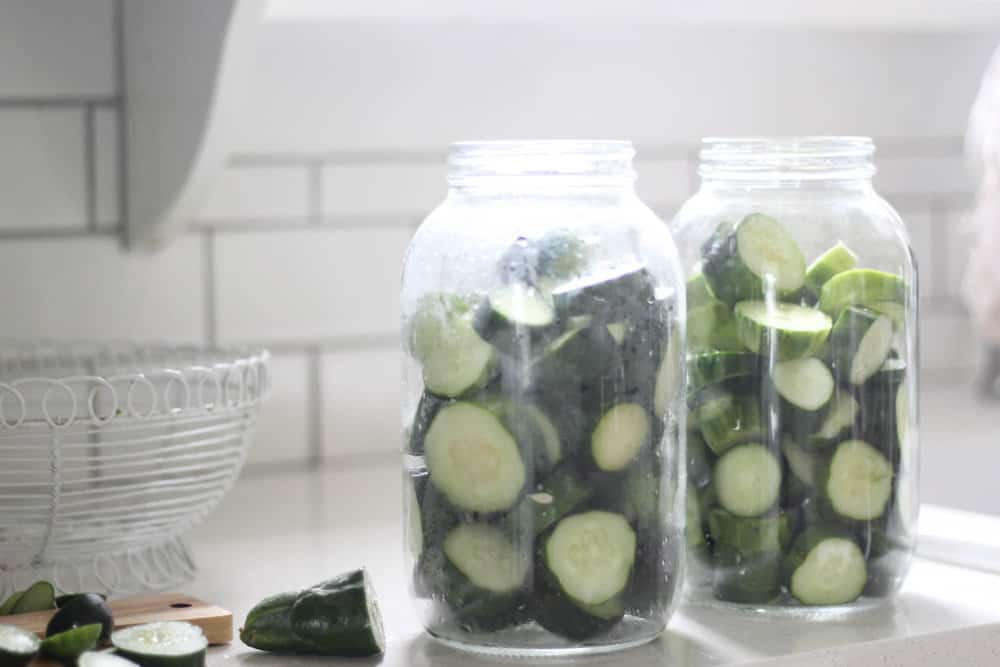 two larger gallon sized mason jars with sliced cucumbers