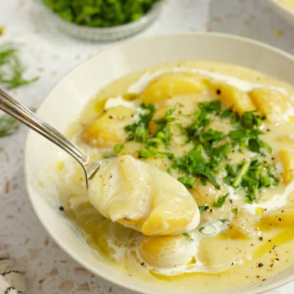 A bowl of potato soup with a spoon scooping out a bit.