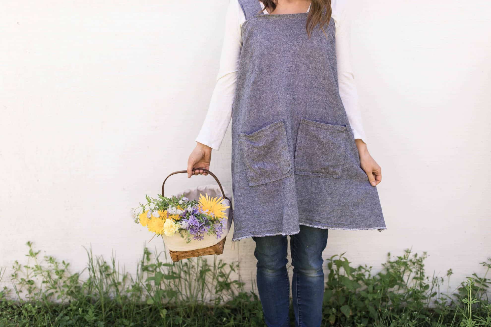 women with a DIY apron holding a basket of flowers