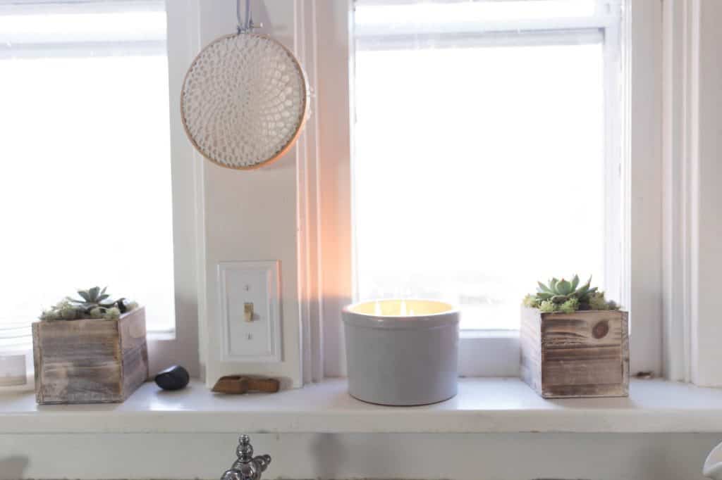 DIY Beeswax Candle with multiple wicks in an antique crock sitting in the windowsill