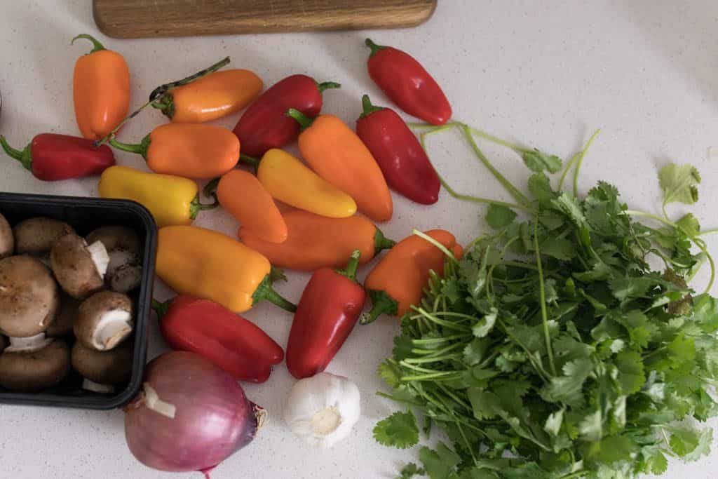 peppers, cilantro, onions on a white countertop