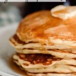 close up photo of half of a stack of sourdough pancakes stacked on a plate and topped with butter and maple syrup