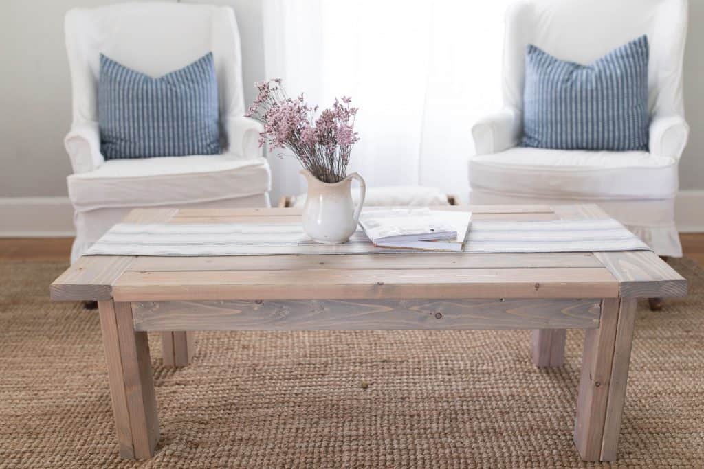 farmhouse coffee table with table runner and a vase of flowers- diy coffee table plans