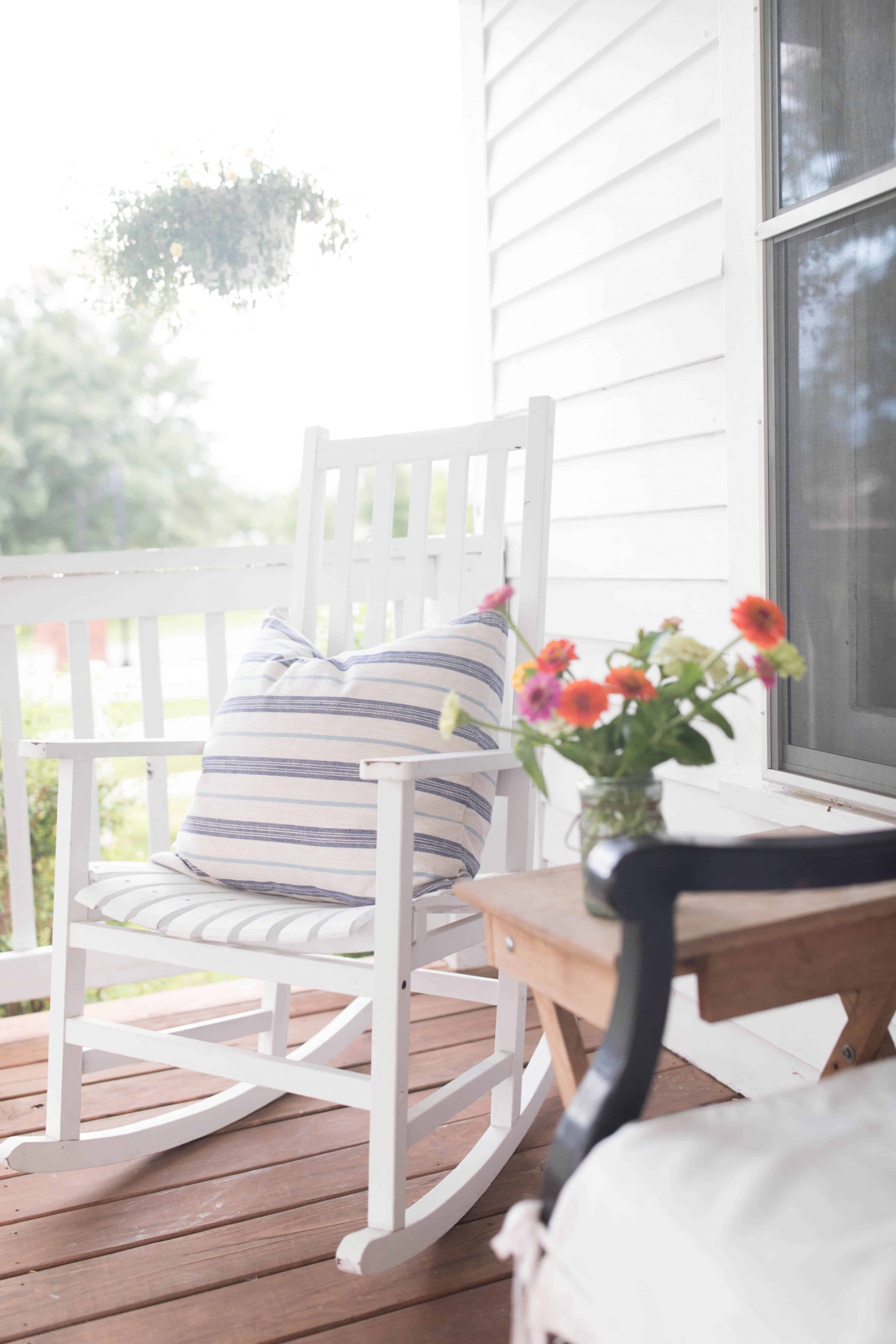 White rocking chair with blue striped pillow on porch