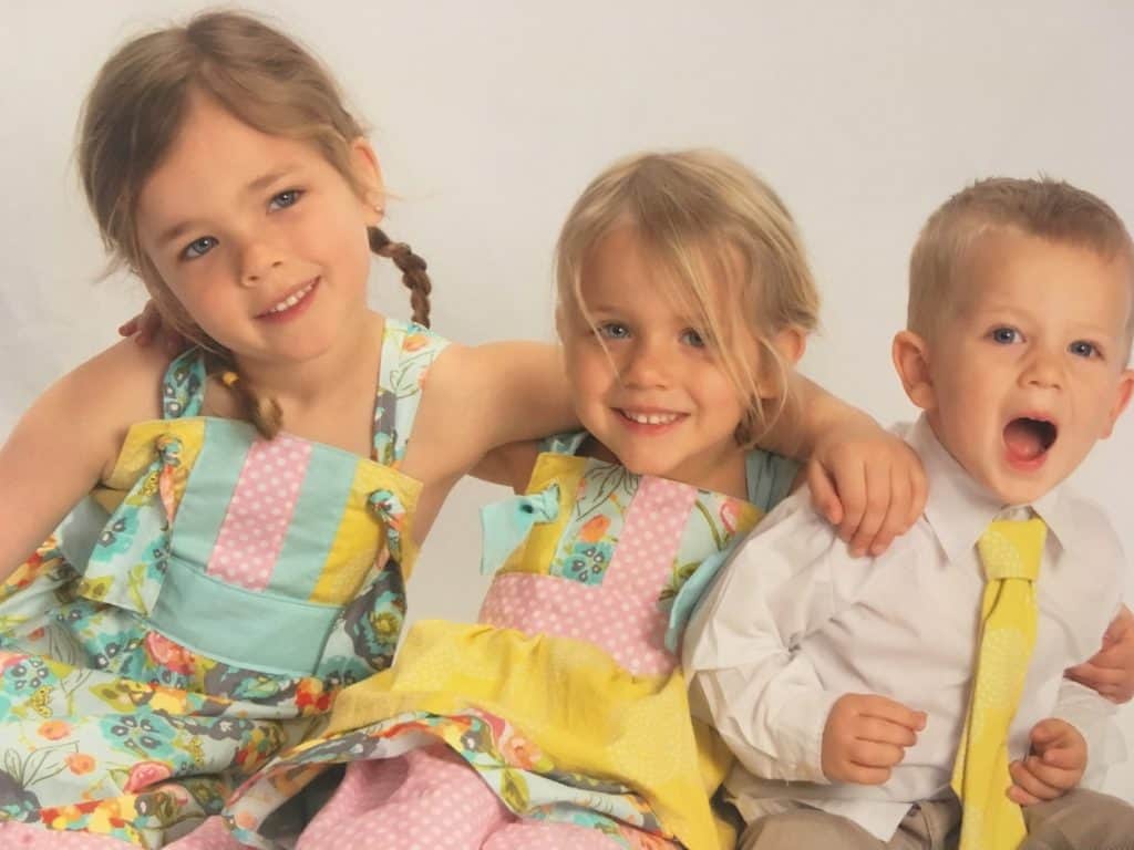 two little girls wearing homemade dresses and a little boy wearing a matching tie