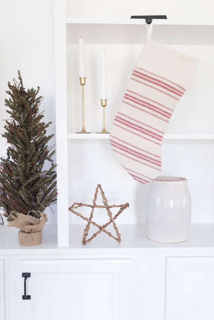 and red and white stripped Christmas stocking hangin on a shelf.