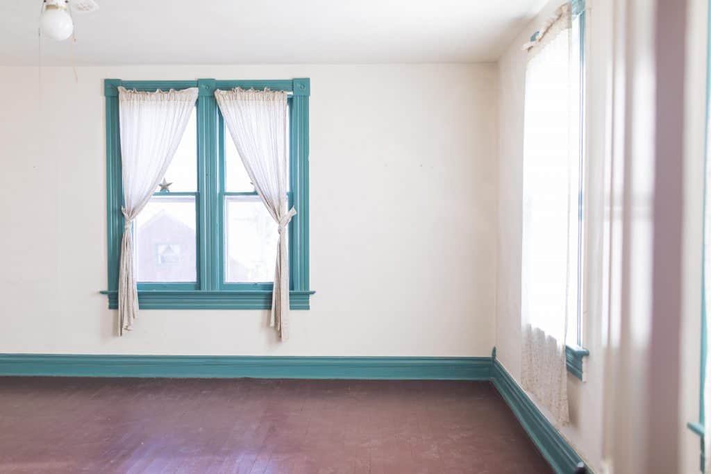 farmhouse bedroom before photos with fluted window trim and brown painted wood floors pine floors 