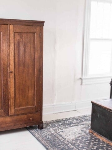 farmhouse style bedroom painted floors antique armoire blue rug chandelier