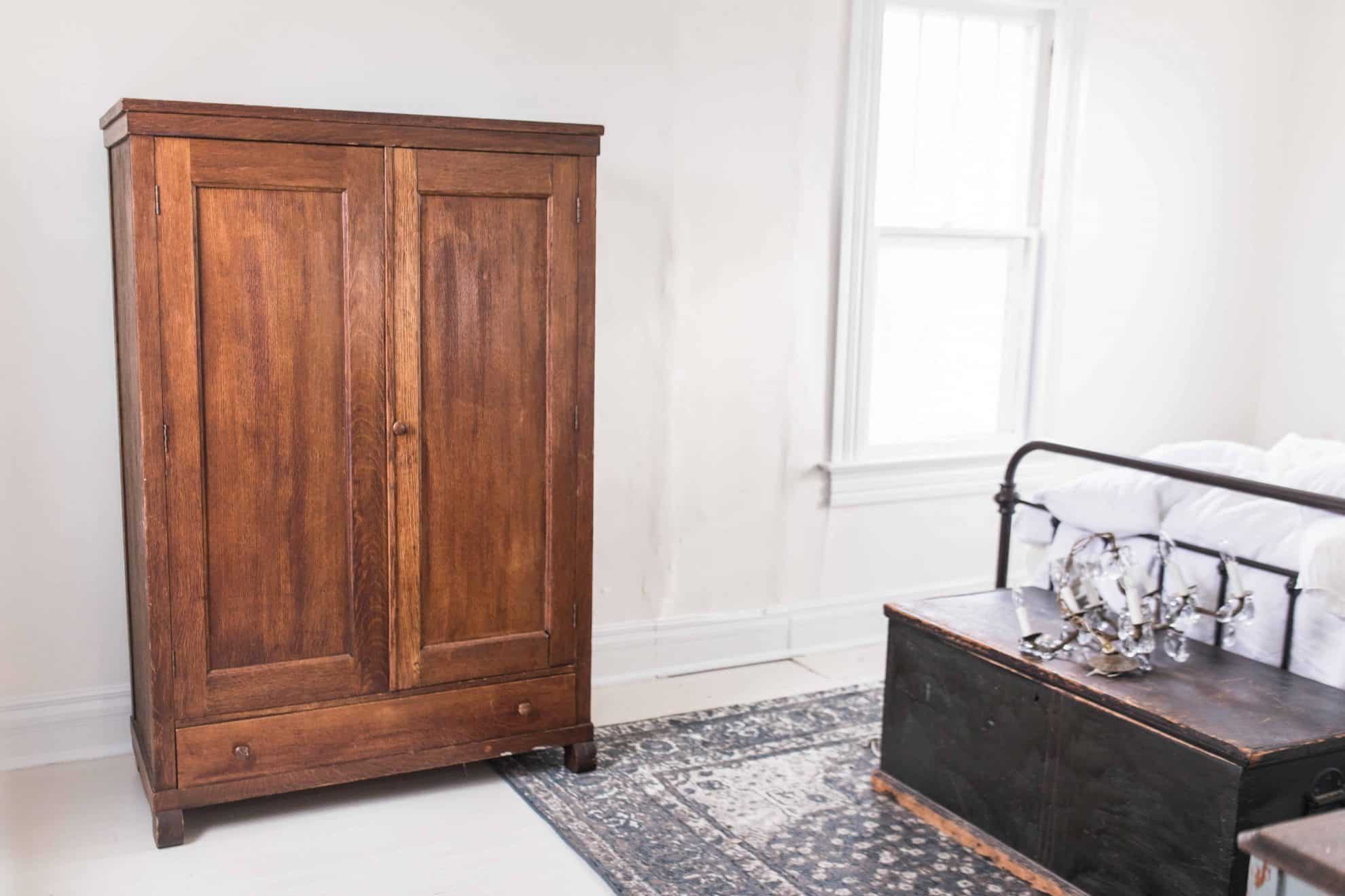 farmhouse style bedroom painted floors antique armoire blue rug chandelier