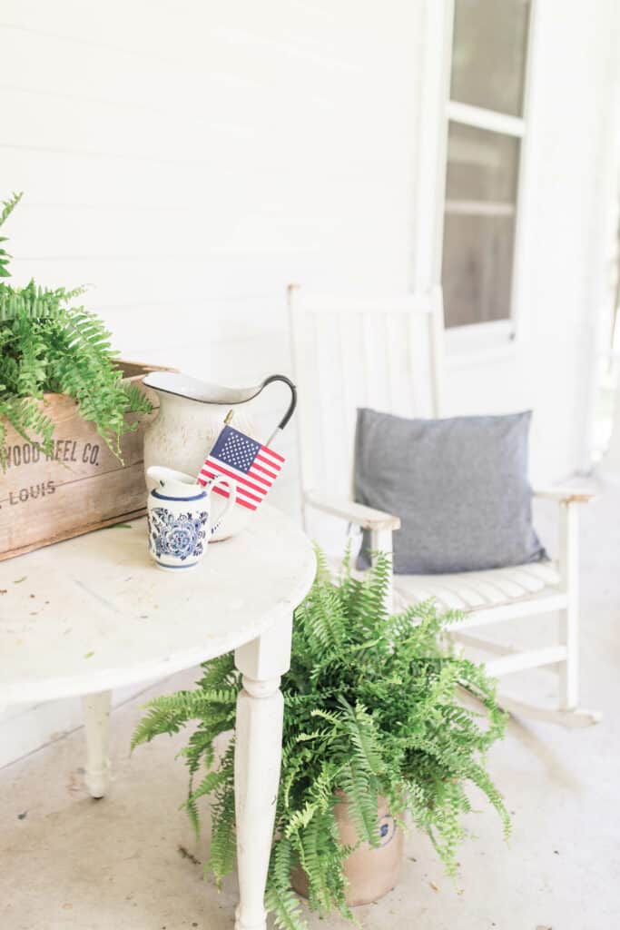 white farmhouse table with ferns in a vintage crate and vintage pitchers on top, 