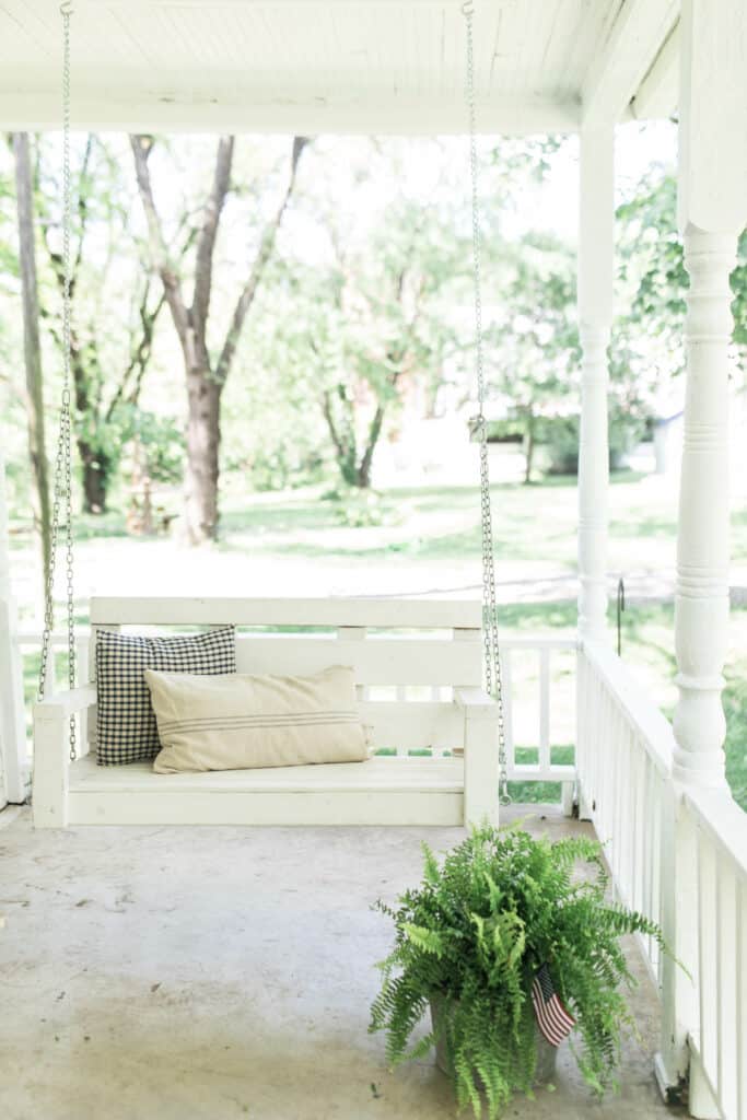 farmhouse pillows on a white porch swing