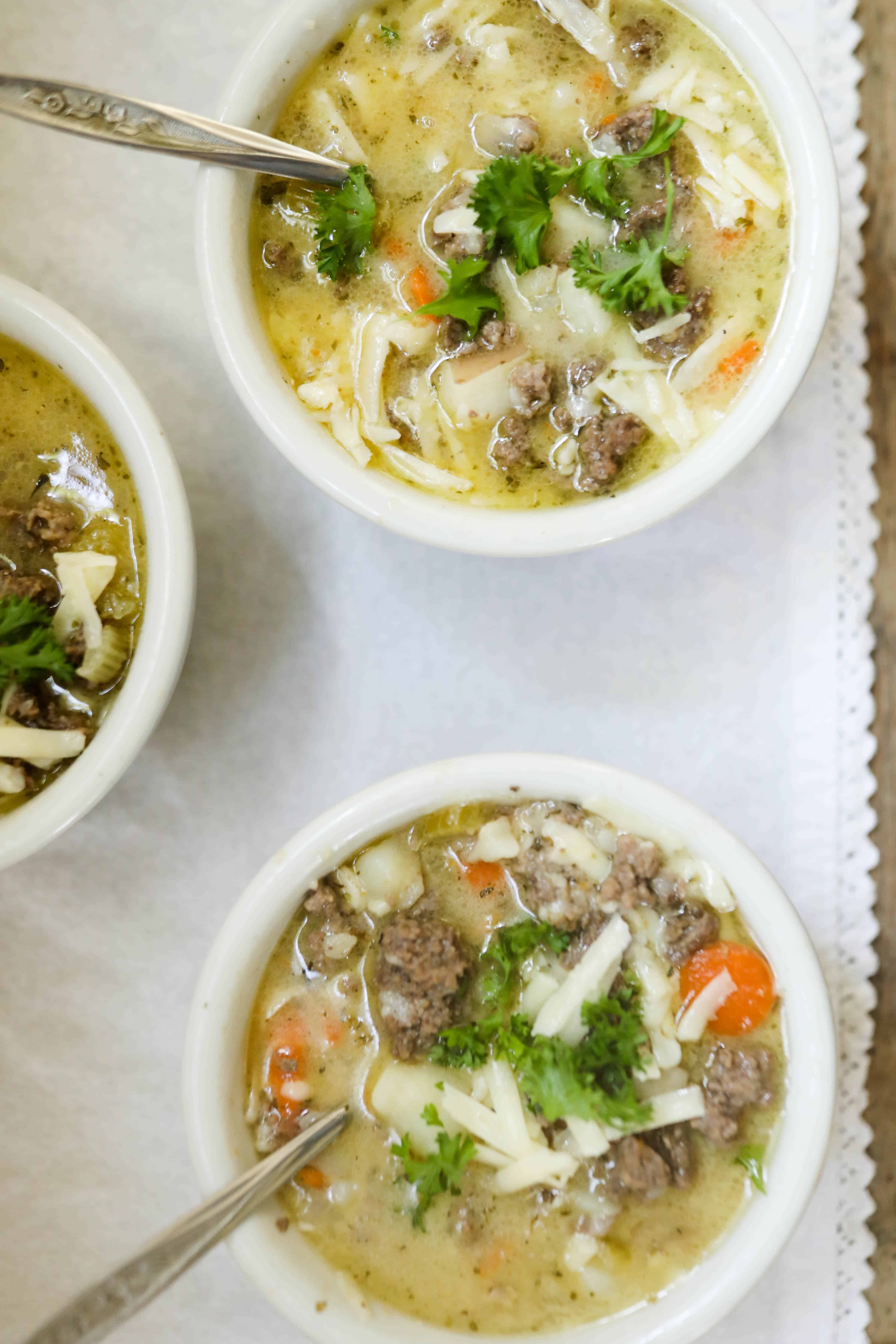 A bowl of cheeseburger soup with a spoon next to it on a white countertop. 