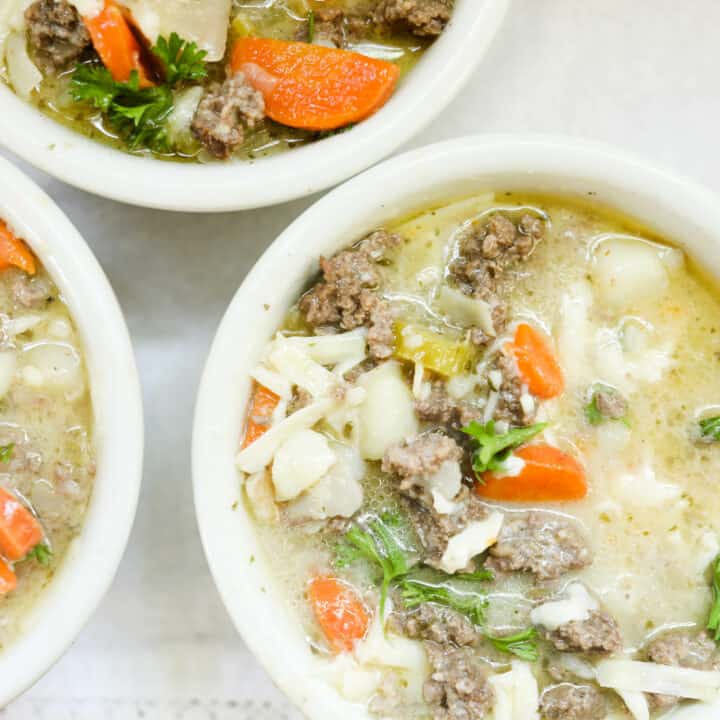 3 bowls of cheeseburger soup topped with cheese and parsley in white bowls
