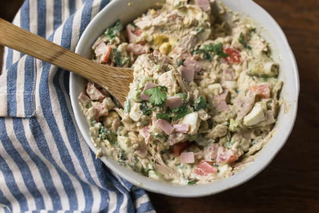 cob chicken salad in a large white bowl with on a blue and white stripped towel