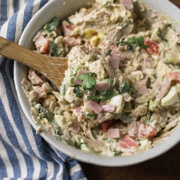 cob chicken salad in a large white bowl with on a blue and white stripped towel