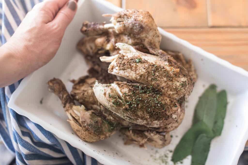 Instant Pot Whole chicken on a white platter with bay leaves