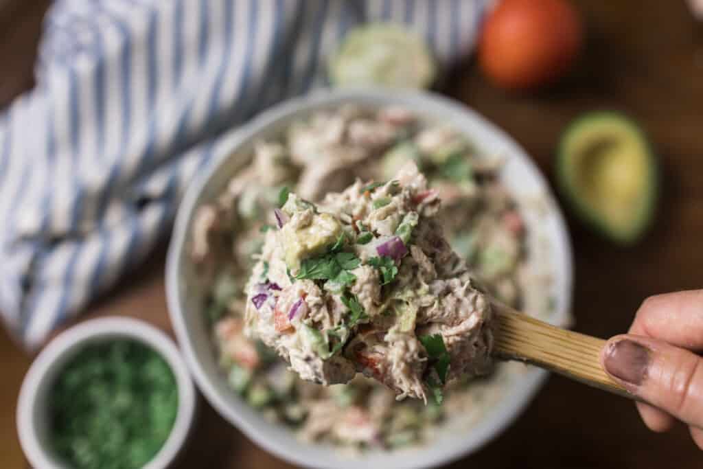 southwest chicken salad with a wooden spoon scooping out a helping