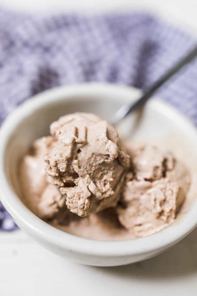 spoon scooping paleo pumpkin spice ice cream from a white bowl