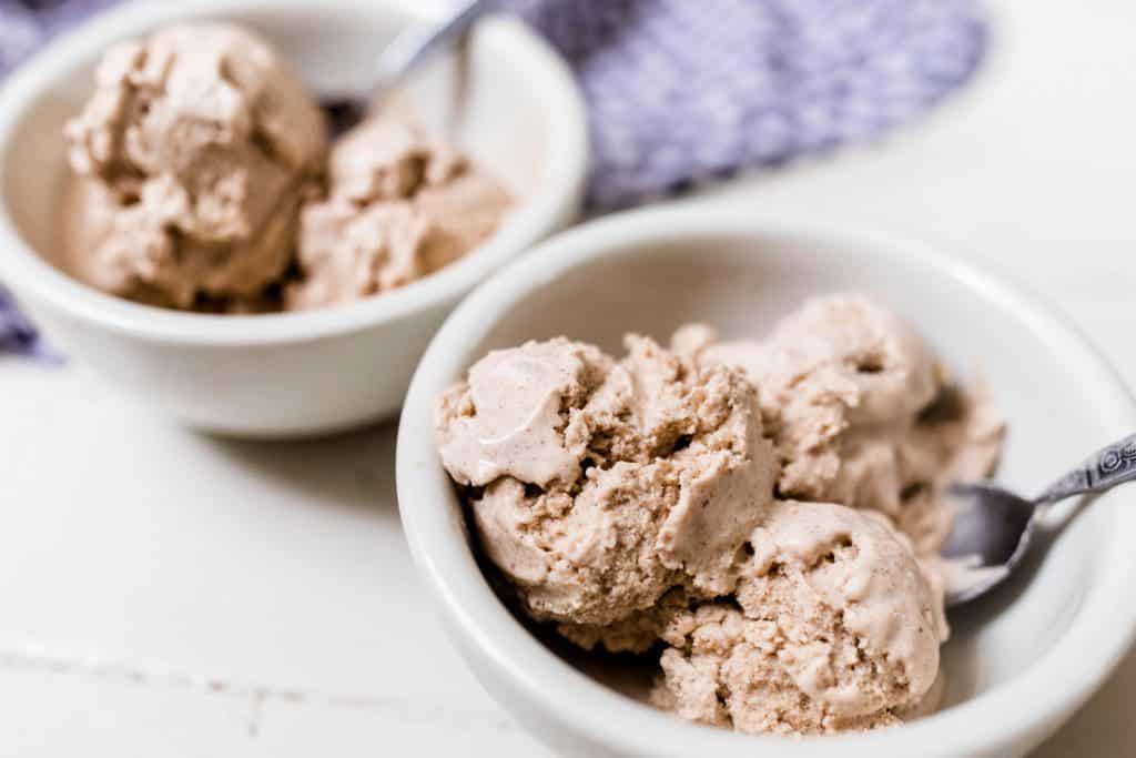 pumpkin spice ice cream in white bowls on a white counter with a blue towel