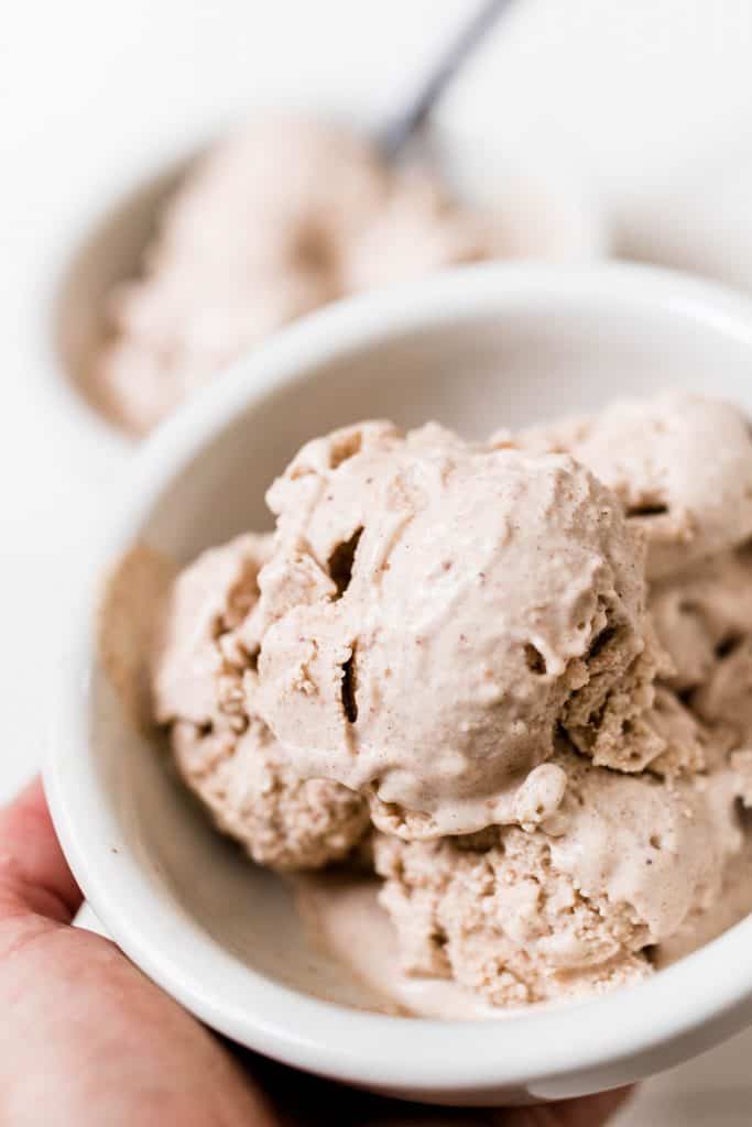 hand holding a bowl of pumpkin spice ice cream sweetened with dates