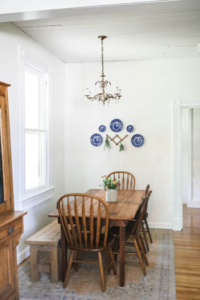 farmhouse eat-in kitchen with farmhouse table with antique chairs on a vintage rug next to a wooden antique hutch