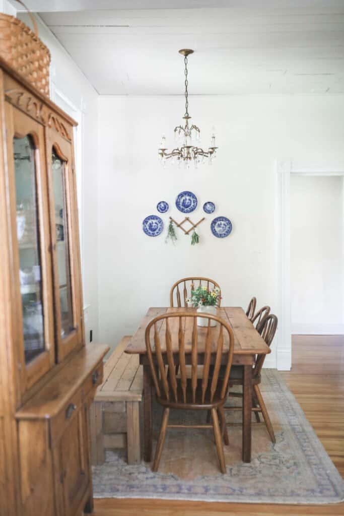 Farmhouse kitchen table with wood chairs and a blue and white plate wall