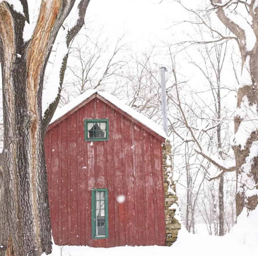 red farmhouse cottage with green trim on a snowy winter day